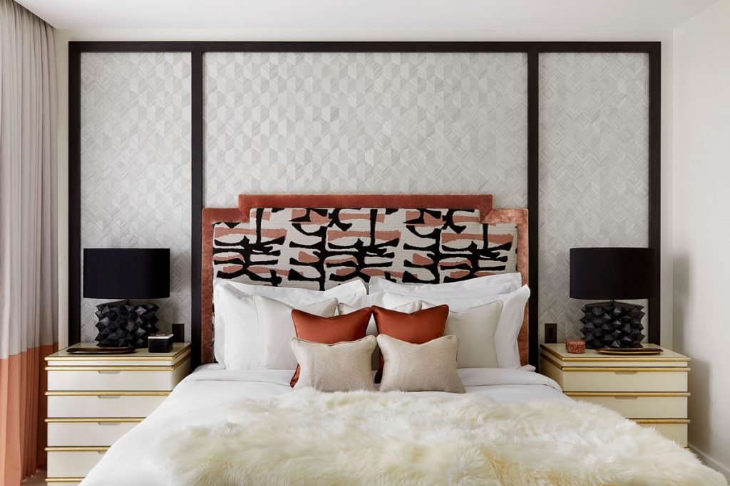 Close up of bedroom furnishings with artistic headboard and luxury bedding