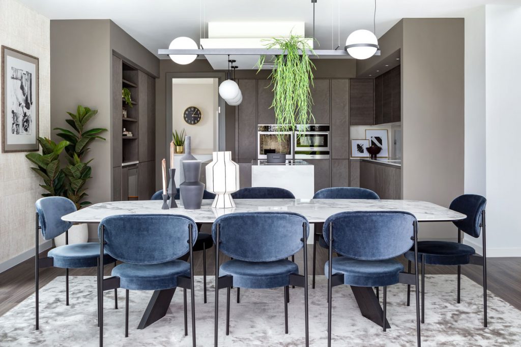 Modern dining room interior setting with velvet blue seating and grey kitchen cupboards