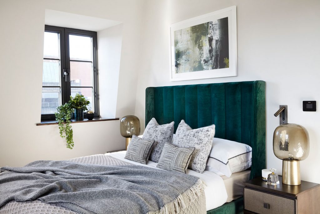 Bedroom interior with green velvet headboard and gold details