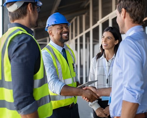 Smiling,Engineer,Shaking,Hands,At,Construction,Site,With,Happy,Architect.